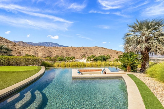 view of pool with a mountain view and a hot tub