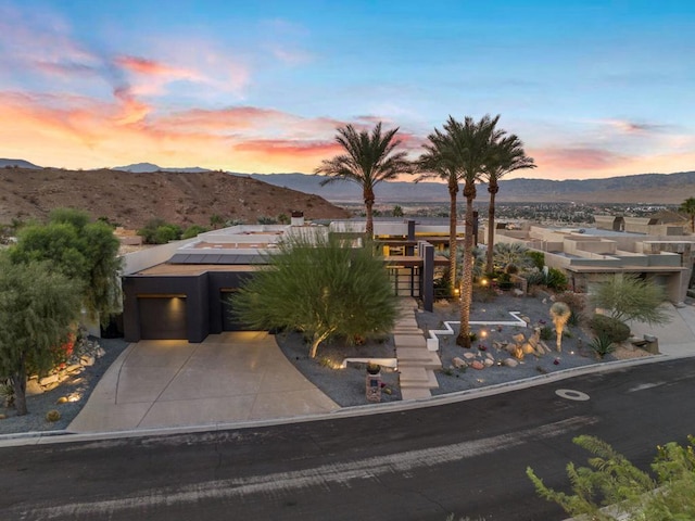 view of front facade featuring a mountain view, a garage, and solar panels