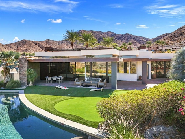 rear view of property with a mountain view, a patio, and an outdoor hangout area