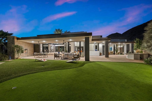 back house at dusk with an outdoor living space and a patio