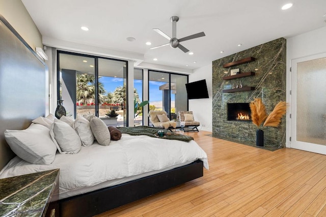 bedroom with ceiling fan, access to exterior, light wood-type flooring, and a fireplace