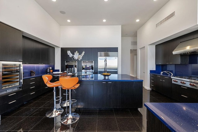 kitchen with wine cooler, a towering ceiling, extractor fan, and appliances with stainless steel finishes