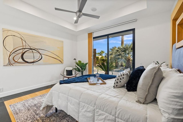 bedroom featuring hardwood / wood-style floors, ceiling fan, and a tray ceiling