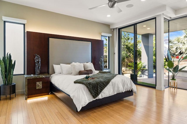 bedroom featuring access to outside, ceiling fan, expansive windows, and light hardwood / wood-style floors