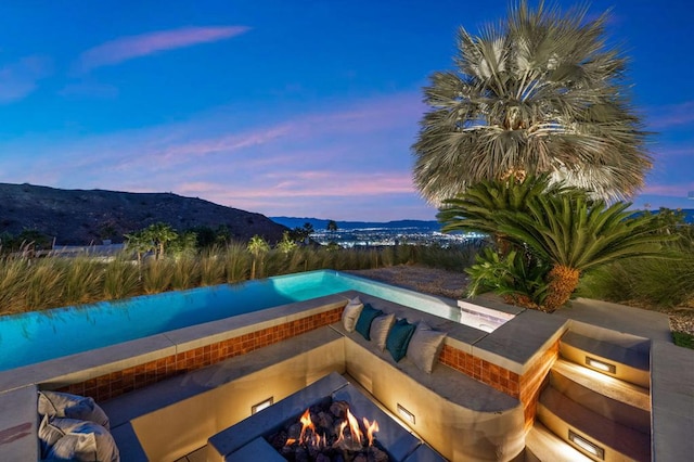 patio terrace at dusk with a mountain view and an outdoor fire pit