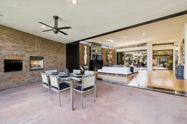 dining space with ceiling fan, a fireplace, and a textured ceiling