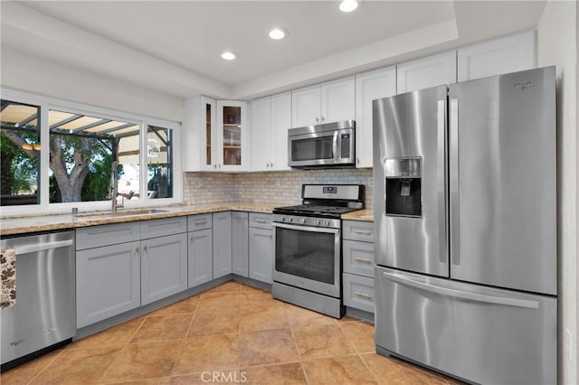 kitchen with appliances with stainless steel finishes, gray cabinets, and light stone counters