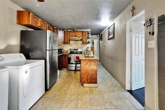 kitchen with stainless steel appliances, a kitchen island, and washing machine and clothes dryer