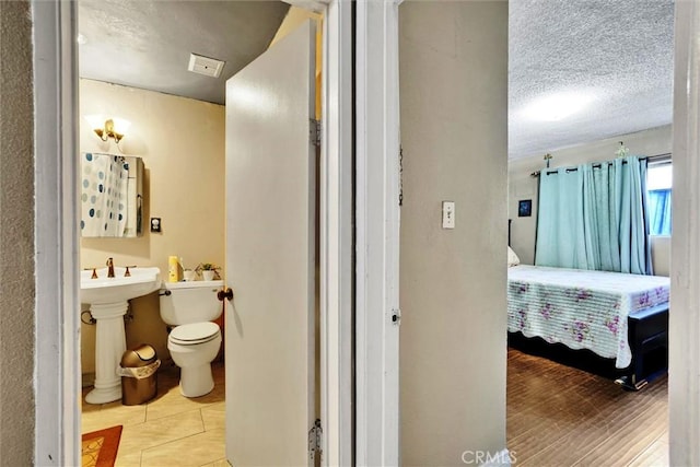 bathroom with a textured ceiling, hardwood / wood-style flooring, toilet, and sink