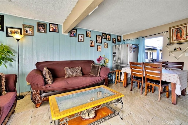 tiled living room featuring wood walls, beamed ceiling, and a textured ceiling