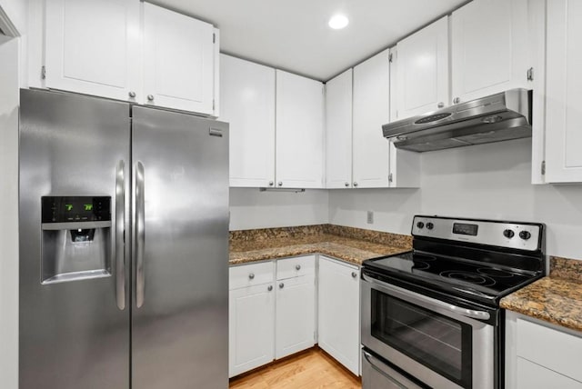 kitchen with white cabinets, light hardwood / wood-style floors, dark stone countertops, and appliances with stainless steel finishes