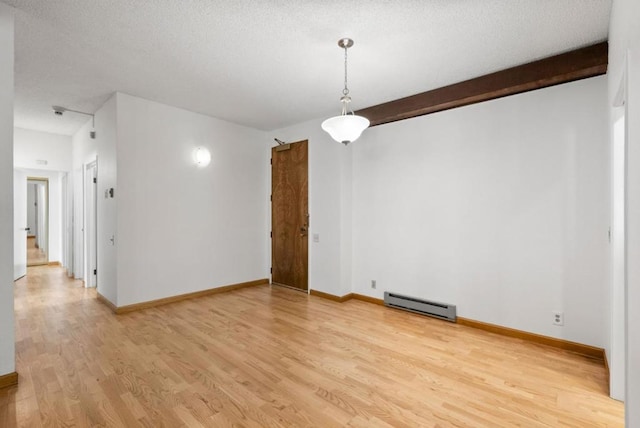 spare room featuring beam ceiling, light wood-type flooring, a textured ceiling, and a baseboard heating unit