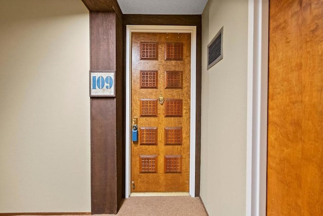 hall featuring light colored carpet and a textured ceiling