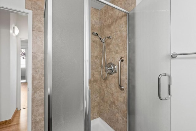 bathroom with wood-type flooring and a shower with shower door