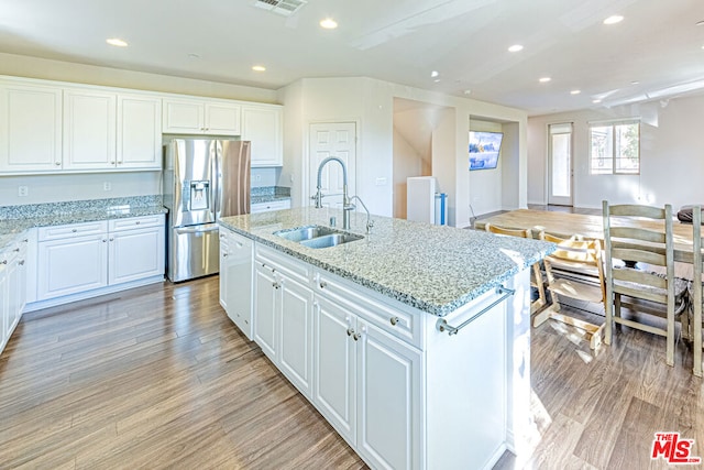 kitchen with stainless steel refrigerator with ice dispenser, an island with sink, white cabinets, and sink