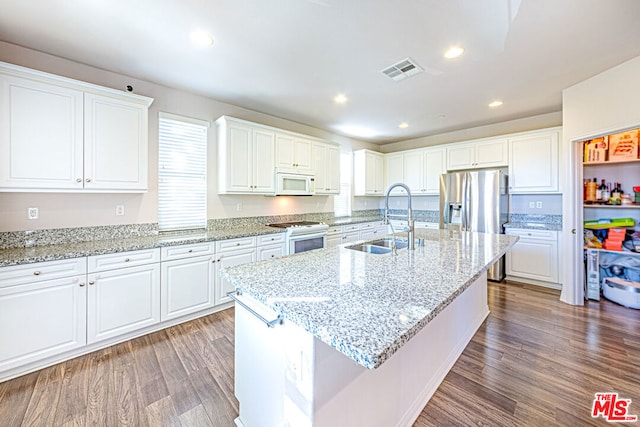 kitchen with an island with sink, white cabinets, sink, and white appliances