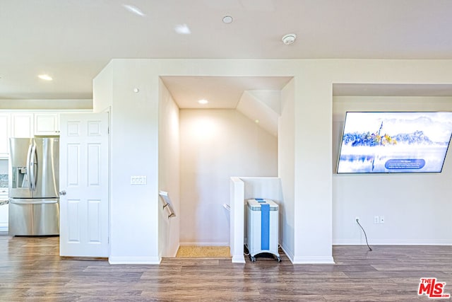 interior space with stainless steel fridge with ice dispenser and hardwood / wood-style flooring