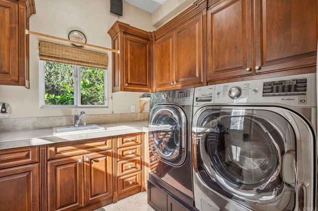 laundry room featuring washing machine and dryer, sink, light tile patterned flooring, and cabinets