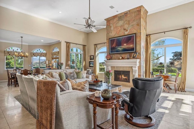 tiled living room with plenty of natural light, a large fireplace, ornamental molding, and ceiling fan with notable chandelier