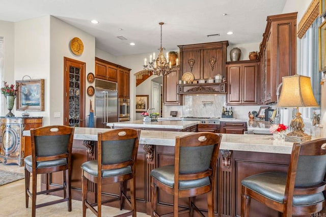 kitchen with a kitchen bar, stainless steel appliances, and an inviting chandelier