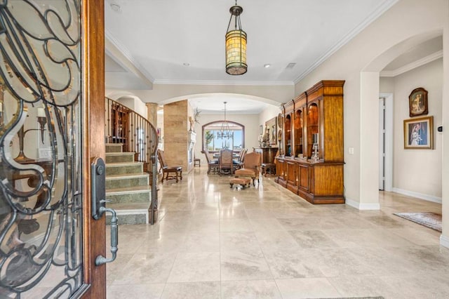 entrance foyer with ornate columns, crown molding, and a chandelier