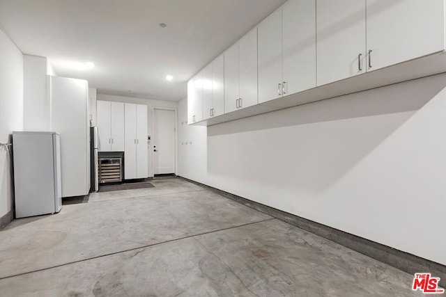 garage featuring stainless steel refrigerator, wine cooler, and white fridge