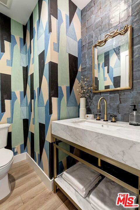 bathroom featuring toilet, decorative backsplash, hardwood / wood-style floors, and sink