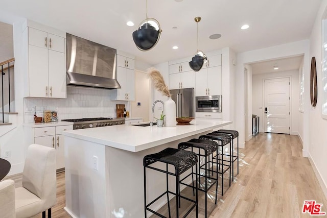 kitchen with white cabinets, appliances with stainless steel finishes, and wall chimney range hood