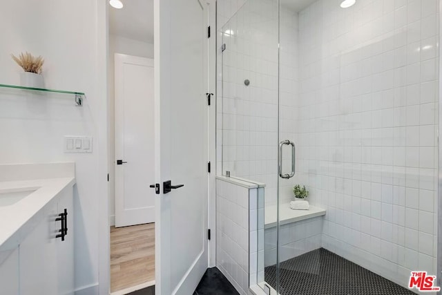 bathroom with a shower with door, vanity, and wood-type flooring