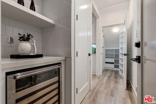 interior space with backsplash, light hardwood / wood-style floors, and beverage cooler