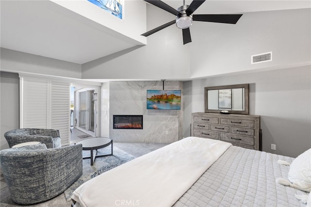 bedroom featuring a high ceiling, ceiling fan, and a high end fireplace