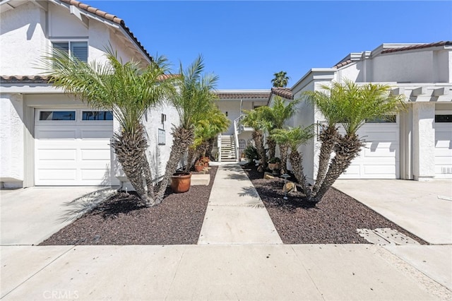 view of front of property featuring stucco siding, a tile roof, an attached garage, and driveway