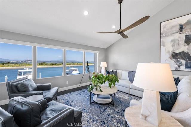 living room featuring ceiling fan, a water view, and vaulted ceiling