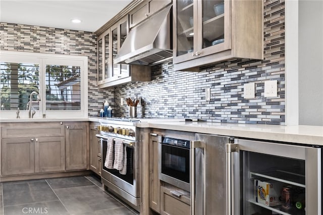 kitchen with tasteful backsplash, sink, stainless steel stove, and beverage cooler