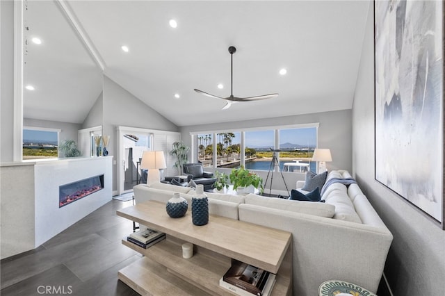 living area with lofted ceiling, a glass covered fireplace, recessed lighting, and plenty of natural light