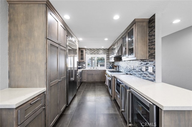 kitchen featuring wine cooler, range hood, premium appliances, a peninsula, and decorative backsplash