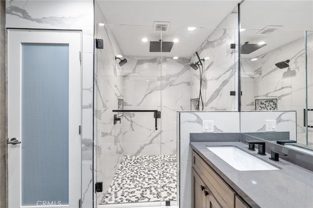 bathroom featuring a marble finish shower, visible vents, and vanity