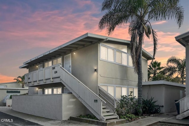 property exterior at dusk featuring a balcony