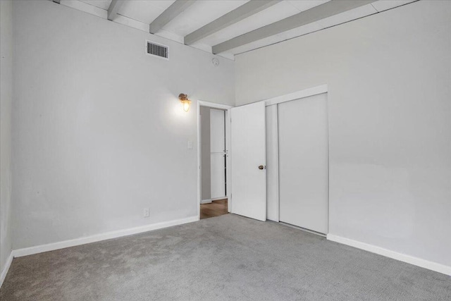 unfurnished room featuring beamed ceiling and carpet