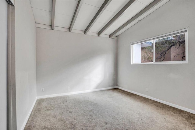 empty room with carpet floors and lofted ceiling with beams