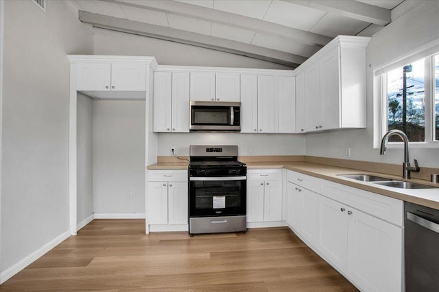 kitchen featuring light hardwood / wood-style flooring, sink, lofted ceiling with beams, white cabinetry, and appliances with stainless steel finishes