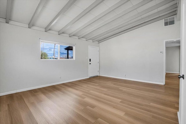 spare room with lofted ceiling with beams and light wood-type flooring