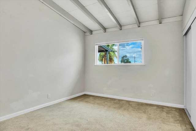 empty room featuring lofted ceiling with beams and carpet floors