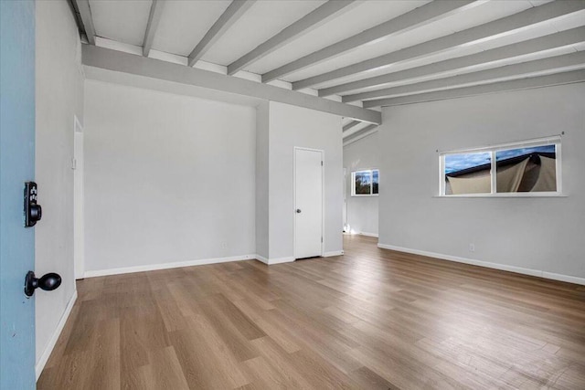 empty room featuring wood-type flooring and vaulted ceiling with beams