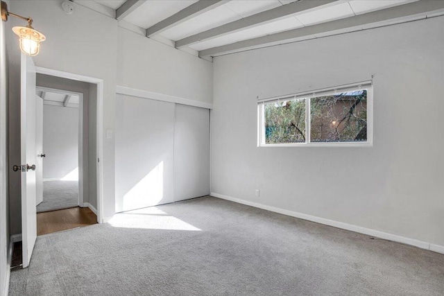 interior space with a closet, beam ceiling, and carpet flooring