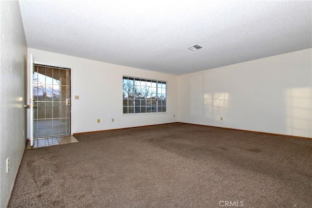 empty room featuring a textured ceiling and carpet flooring