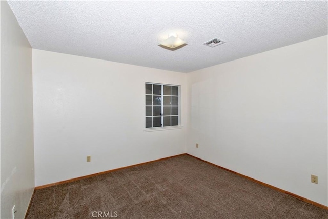 spare room with a textured ceiling and dark colored carpet