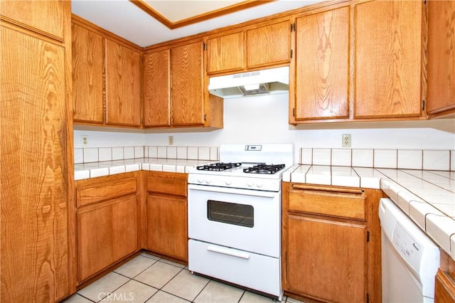 kitchen featuring light tile patterned floors, tile countertops, and white appliances