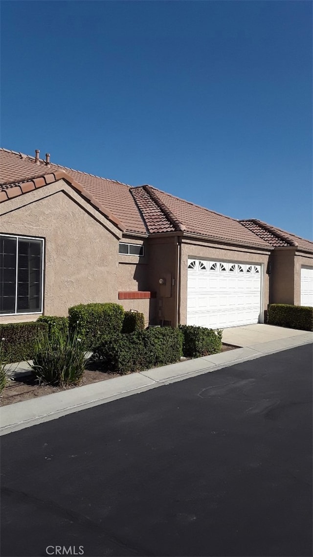 view of front of property featuring stucco siding, a garage, concrete driveway, and a tiled roof