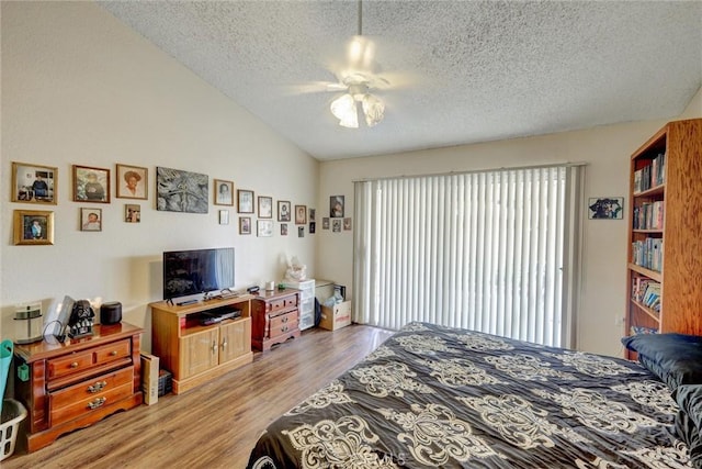 bedroom with light wood-type flooring, a textured ceiling, a ceiling fan, and vaulted ceiling